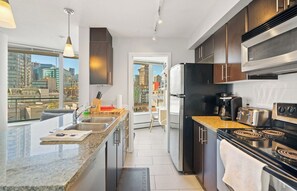 Cozinha moderna com uma ilha grande, eletrodomésticos de aço inoxidável e vista para a cidade.