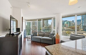 Sala moderna com sofá, mesa de centro e uma grande janela com vista para a cidade.