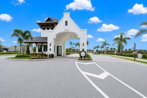 A white building with a large archway, numbered 5776, and a sign indicating a university entrance. - Calsua Golf Club 2BR Lakefront Condo Putt In Paradise (Bradenton)