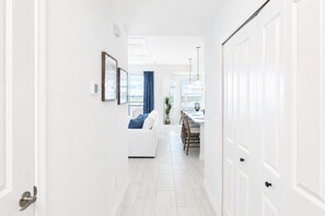 Ein Flur, der in einen Essbereich mit weißem Sofa und Esstisch führt.
