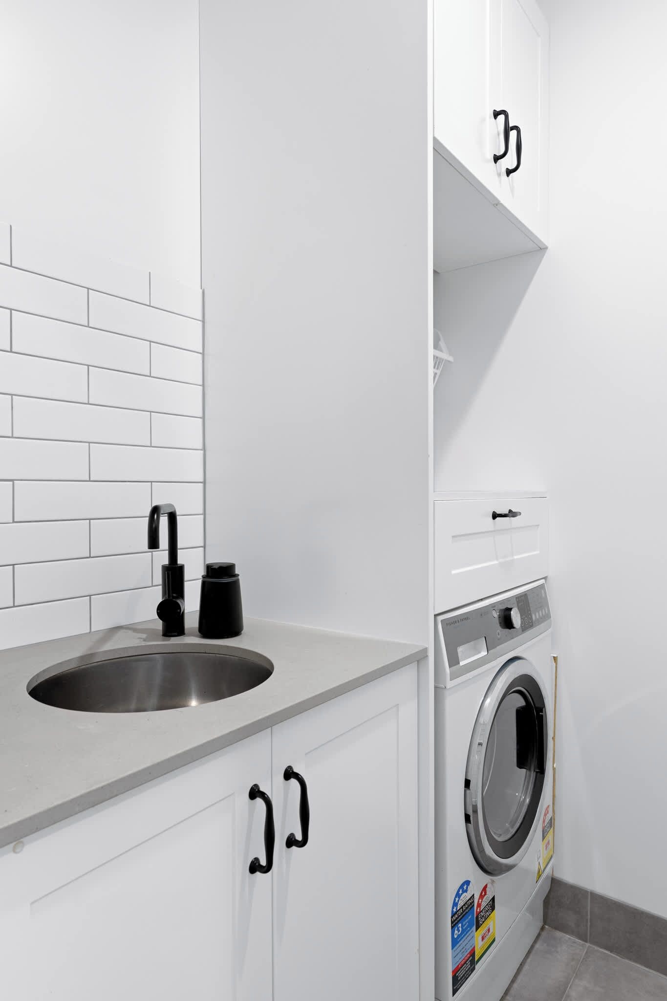 A compact kitchen with a sink, a coffee maker, and a built-in washing machine.