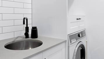 A compact kitchen with a sink, a coffee maker, and a built-in washing machine.