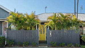 A residential house with a grey picket fence, a yellow door, and a number '15' on the gate. - Pet-friendly cottage near cafes, pubs and parks (Merewether)
