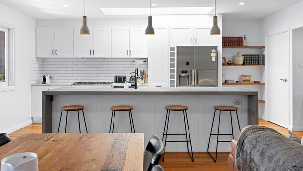 A modern kitchen with white cabinets, a central island with stools, and pendant lighting. - Pet-friendly cottage near cafes, pubs and parks (Merewether)