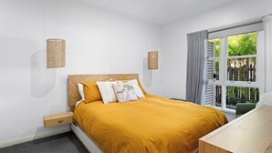 A bedroom with a bed, bedside tables, a window with curtains, and wall-mounted lamps. - Pet-friendly cottage near cafes, pubs and parks (Merewether)