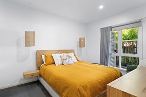 A bedroom with a bed, bedside tables, a window with curtains, and wall-mounted lamps. - Pet-friendly cottage near cafes, pubs and parks (Merewether)