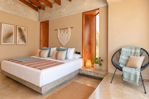 A bedroom with a large bed, a chair, a macrame wall hanging, and framed artwork. - Oceanview Modern home in Organos AmorAmAr LN4 (Organos)