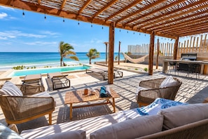 Ein Sitzbereich am Strand mit Pool, Liegestühlen und Grillmöglichkeit.
