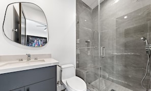 Un baño con inodoro, lavamanos y ducha con puerta de cristal.