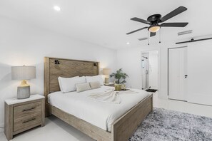 A bedroom with a bed, bedside tables, a ceiling fan, and a door. - Gulf Access Getaway with Heated Pool, Dock, Kayaks and Fun Family Retreat - Salty Serenity - Roelens (Cape Coral)