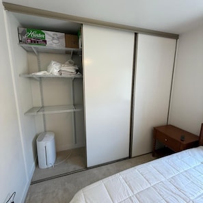 Un dormitorio con cama, armario y una mesita de noche.