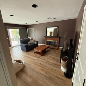 Una sala de estar con sofá, mesa de centro, chimenea y televisor.