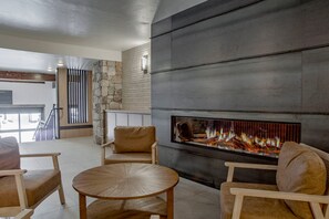 Un salon moderne avec une cheminée, un mur en pierre et des meubles en bois.