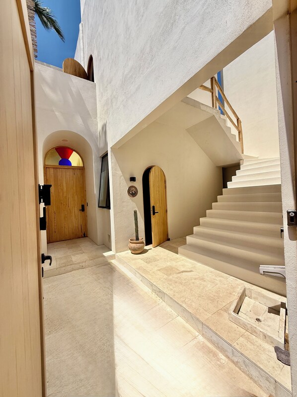 A modern interior with a staircase, a wooden door, and a potted plant.