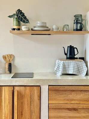 A kitchen counter with a coffee maker, a plant, and various kitchenware.