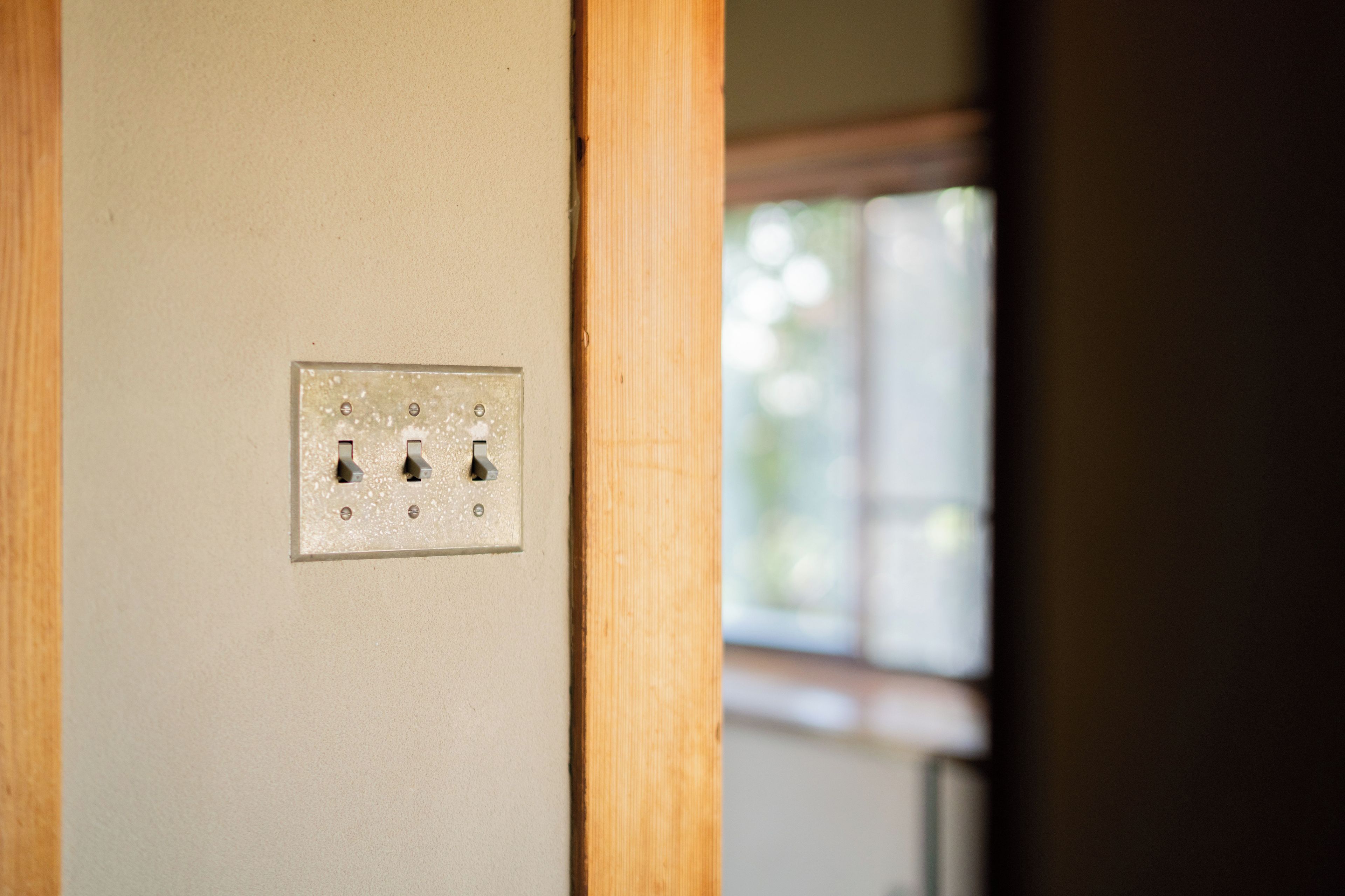 A wall-mounted electrical outlet with three switches and a single socket.