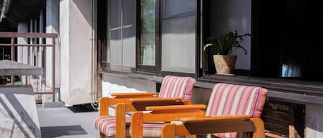 A wooden deck with two striped chairs and a potted plant.
