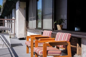 Una terraza de madera con dos sillas a rayas y una planta en maceta.
