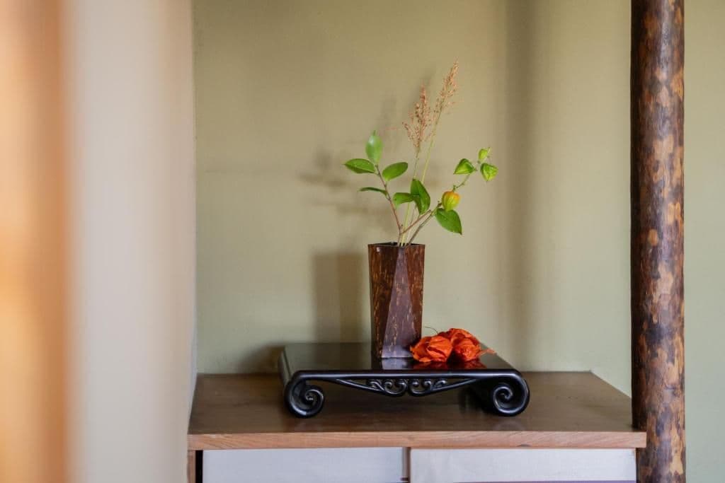 Une table en bois sur laquelle se trouve un vase contenant une plante et un objet décoratif.
