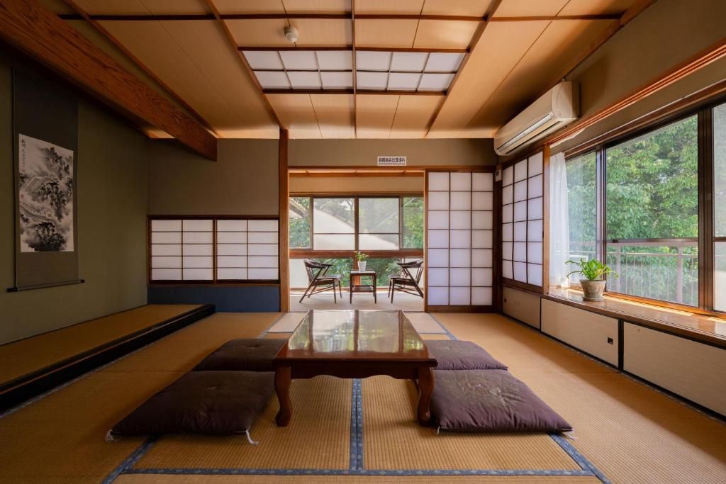 A tatami mat room with a low table, cushions, sliding shoji doors, and a view of greenery outside.