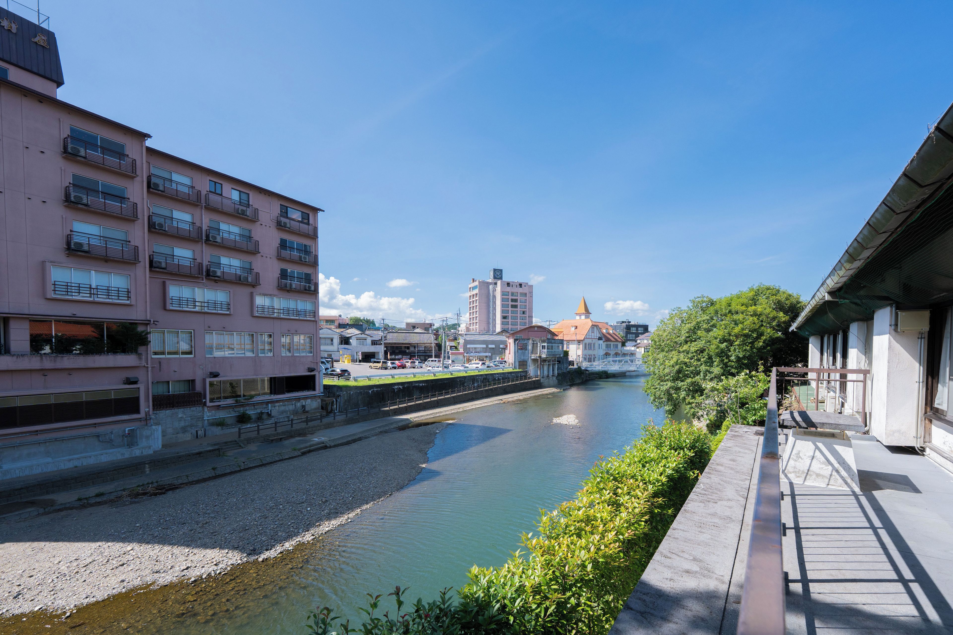 A riverside view with a building featuring multiple balconies and a clear sky.
