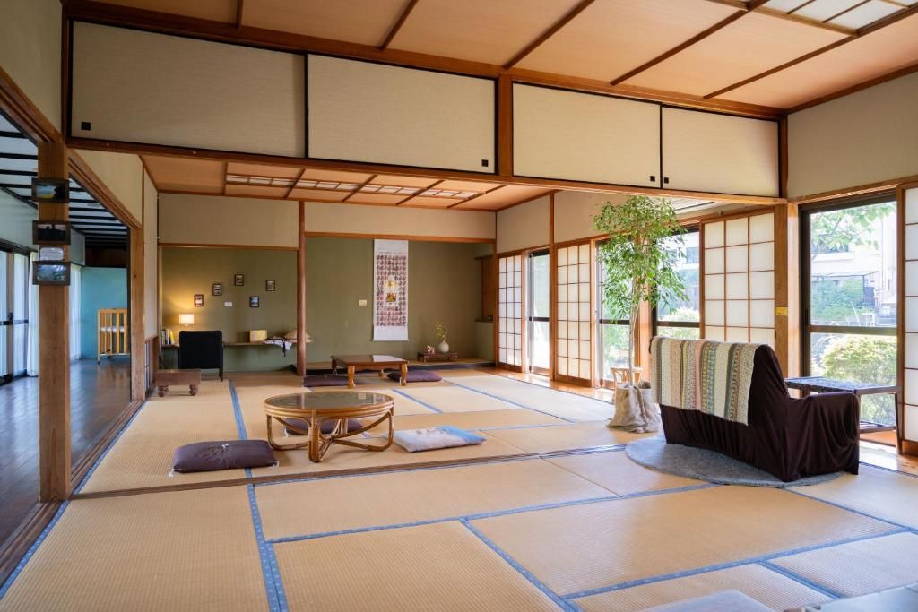Une pièce avec un sol recouvert de tatamis, comprenant une table en tatami, des coussins, une petite table basse et une fenêtre donnant sur un paysage agréable.