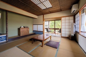 A traditional Japanese room with tatami flooring, a low wooden table, a cushioned bench, and sliding shoji doors. - GUESTHOUSE LAPPY (Ureshino)