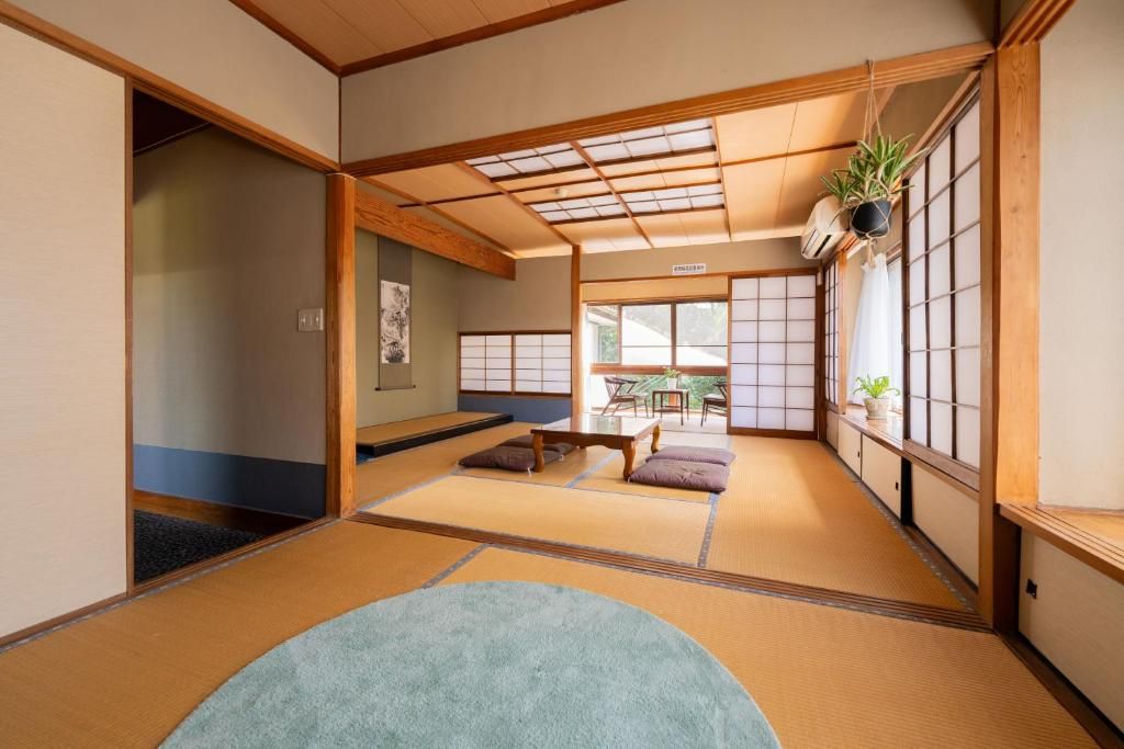 Una habitación con suelo y banco de tatami, una mesita y una ventana con vistas.