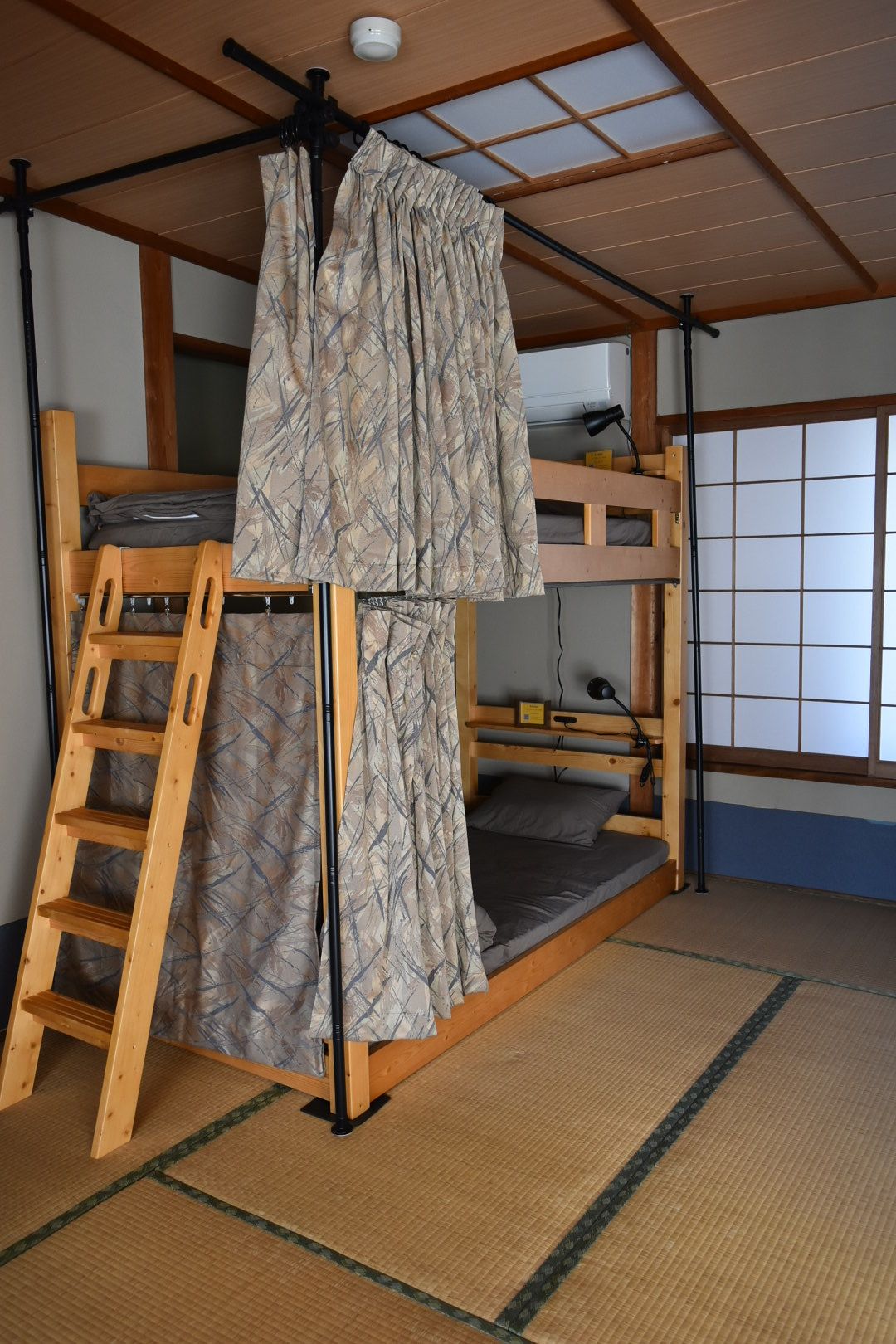 A bunk bed room with a ladder, a ceiling fan, and a window with a grid pattern.