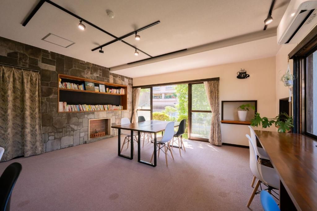A modern interior with a stone fireplace, a dining area with a table and chairs, and a bookshelf.