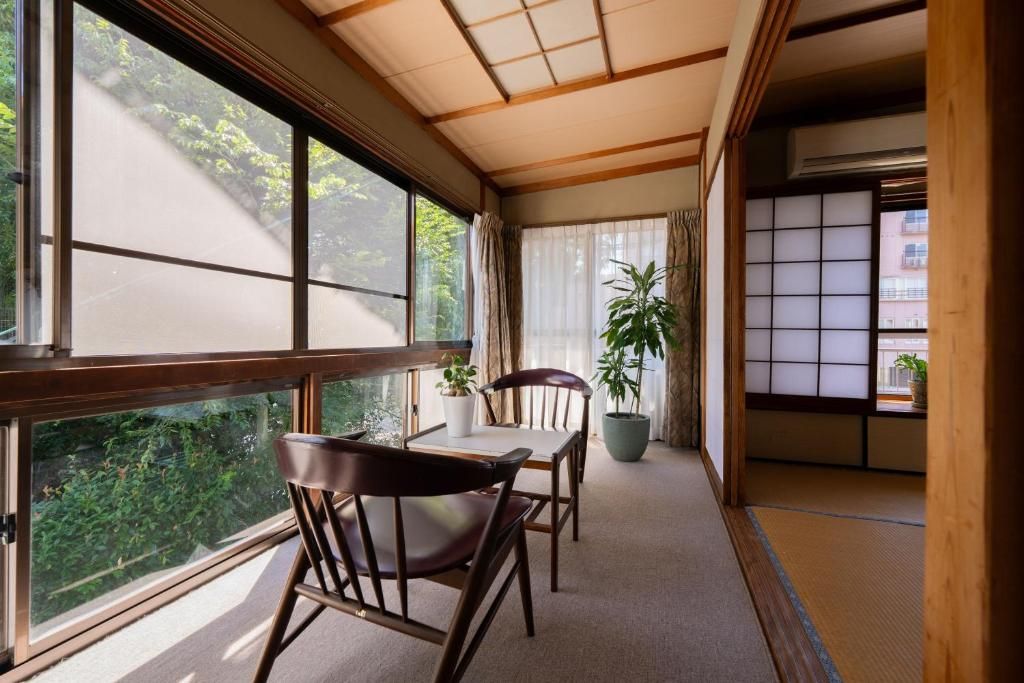 Una habitación japonesa tradicional con suelo de tatami, una mesa baja con sillas, una planta en maceta y una puerta corredera.