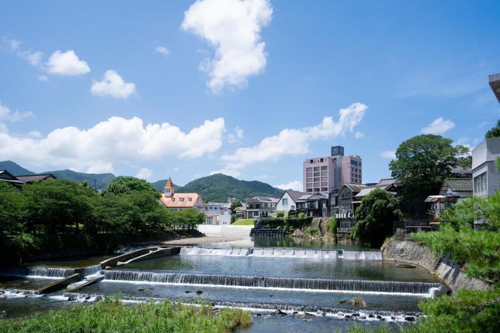 A riverside town with traditional buildings, a modern high-rise, and a series of waterfalls.