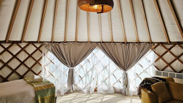 A room with a bed, a sofa, and a hanging light fixture.