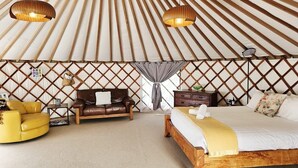 A room with a bed, a sofa, a yellow armchair, and a wooden headboard.
