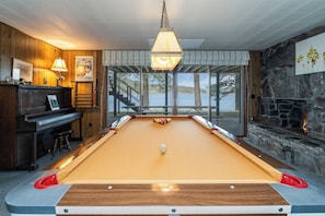 Une table de billard avec vue sur un lac, un piano et une cheminée.