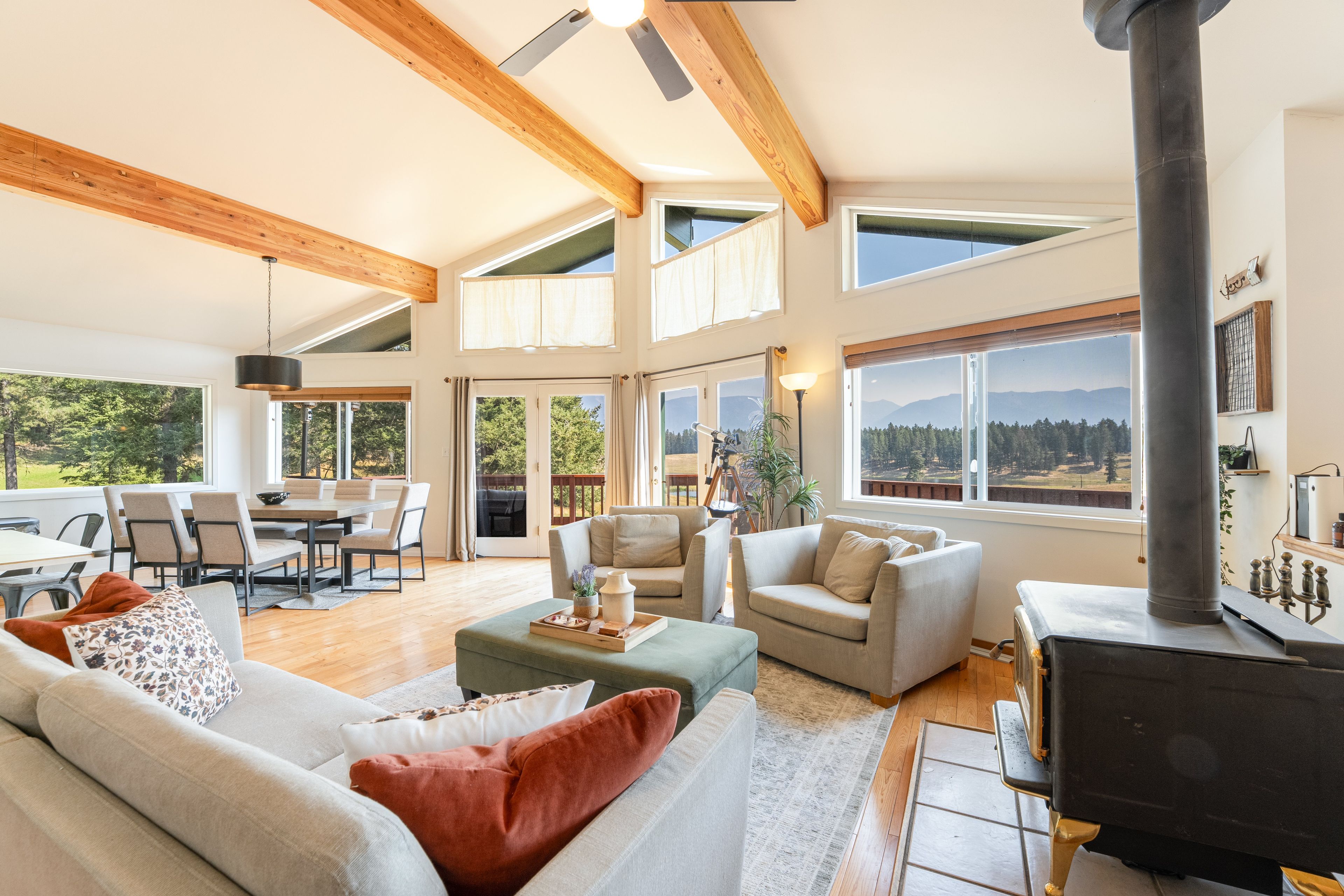 A spacious living room with a fireplace, a dining area, and large windows offering a view of the outdoors.