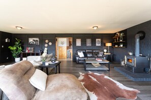 Un salon moderne avec une cheminée, des canapés en cuir, une table basse et un tapis en peau de vache.