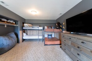 Une chambre à coucher de taille réduite, équipée de lits superposés, d’une télévision et d’une commode.