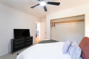 A bedroom with a bed, a black dresser, a ceiling fan, and a walk-in closet. - New! Secluded 9.5-Acre Mountain Retreat with Jewel Basin Views, Near Flathead Lake (Bigfork)