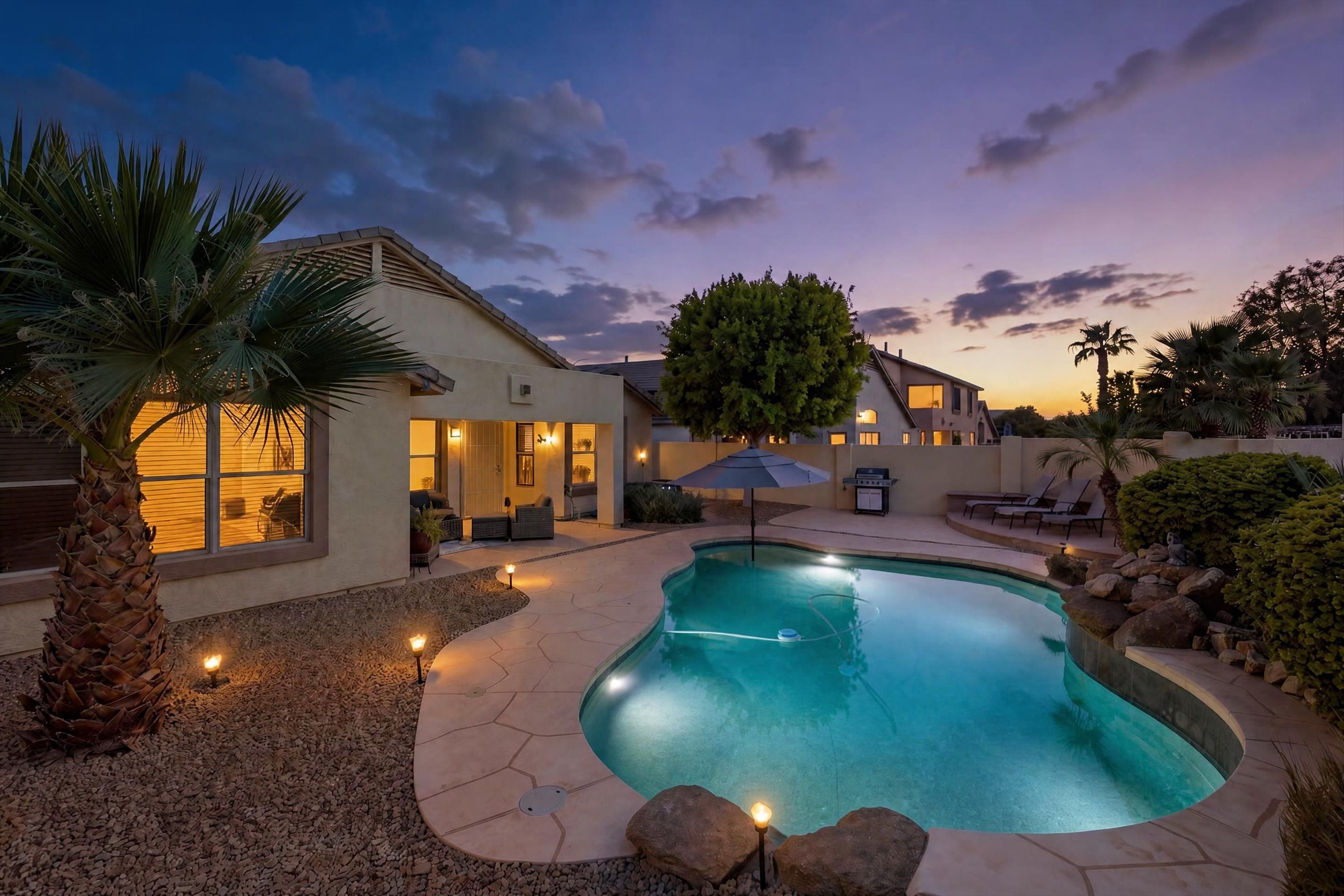 A residential property with a swimming pool, outdoor seating, and a well-maintained garden.