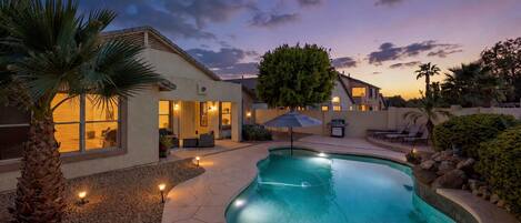 A residential property with a swimming pool, outdoor seating, and a well-maintained garden.