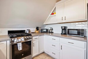 Eine moderne Küche mit Gasherd, Backofen, Mikrowelle und Kaffeemaschine.