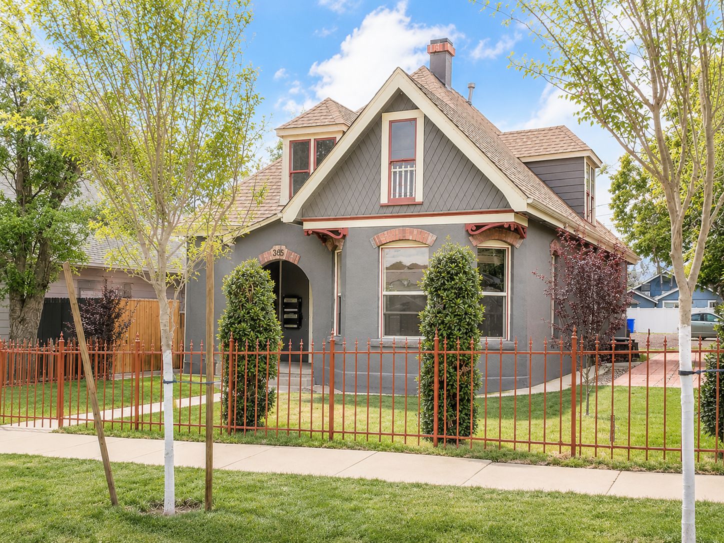 A two-story house with a grey roof, a red front door, and a mailbox.