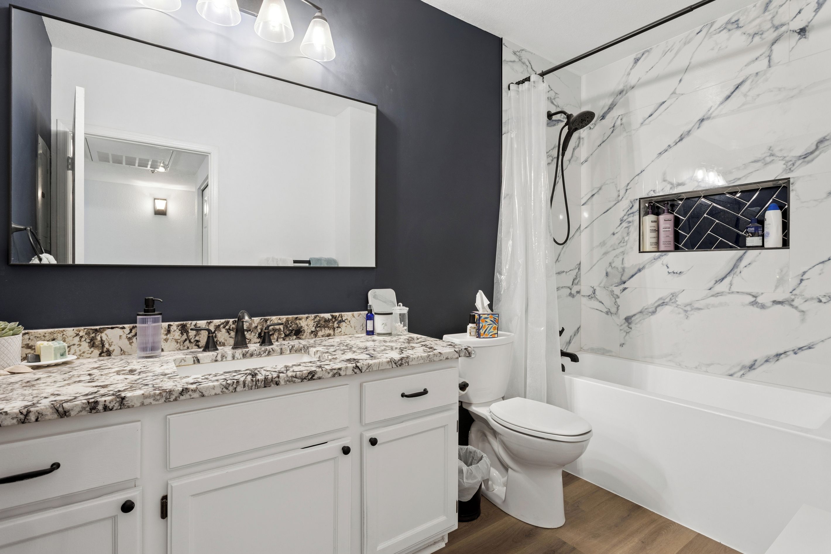 Un baño moderno con lavamanos de mármol, un espejo grande y una ducha con pared de mármol.