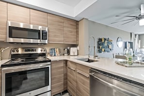 Eine moderne KĂŒche mit EdelstahlgerĂ€ten, HolzschrĂ€nken und einem eingebauten GeschirrspĂŒler.