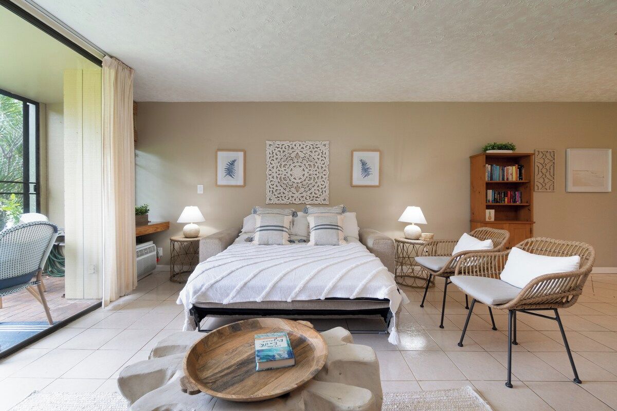 Un dormitorio con una cama, dos mesitas de noche, una estantería, una silla y una ventana.