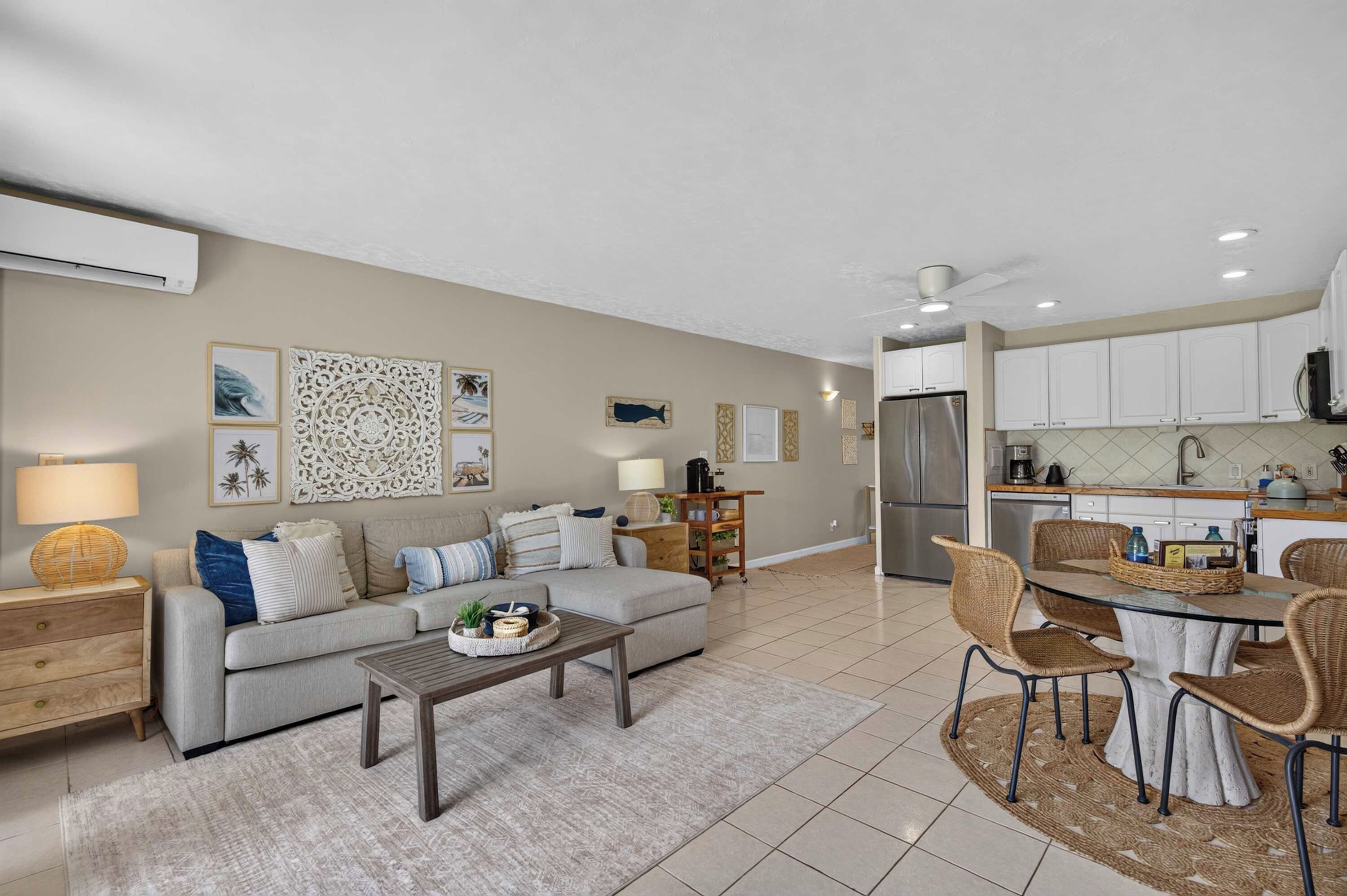 A modern living room with a sofa, coffee table, and a dining area with chairs and a table.