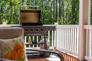 A barbecue grill with a brand name on it, placed on a wooden deck with a white railing. - Two Harbors Contemporary Home, by Heirloom (Two Harbors)