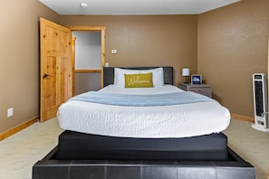A bedroom with a bed, a nightstand, a heater, and a wooden door. - Two Harbors Contemporary Home, by Heirloom (Two Harbors)