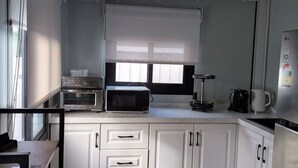 A modern kitchen with white cabinets, a microwave, toaster, and a coffee maker.